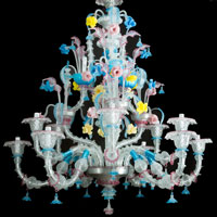 Large Venetian chandelier, multicoloured and transparent glass for 15 light, in curved and bowed shape,  mouth blown glass, partly canted, decorated with flowers, leaves, branches, spouts finials in red, blue, yellow and pink glass; with several hanging elements on metal strings; later electrification not tested;  in perfect condition; Venice around 1900